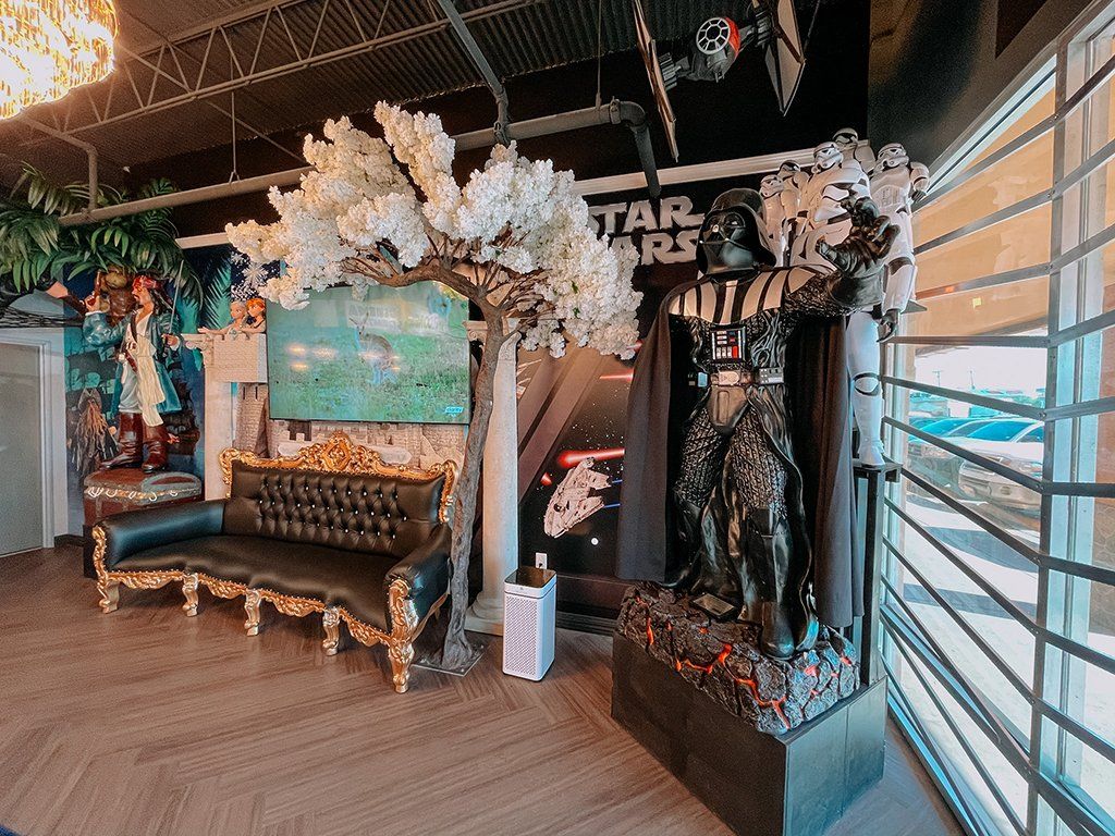 Star Wars-themed room with Darth Vader statue, a black couch, and a decorative white tree.