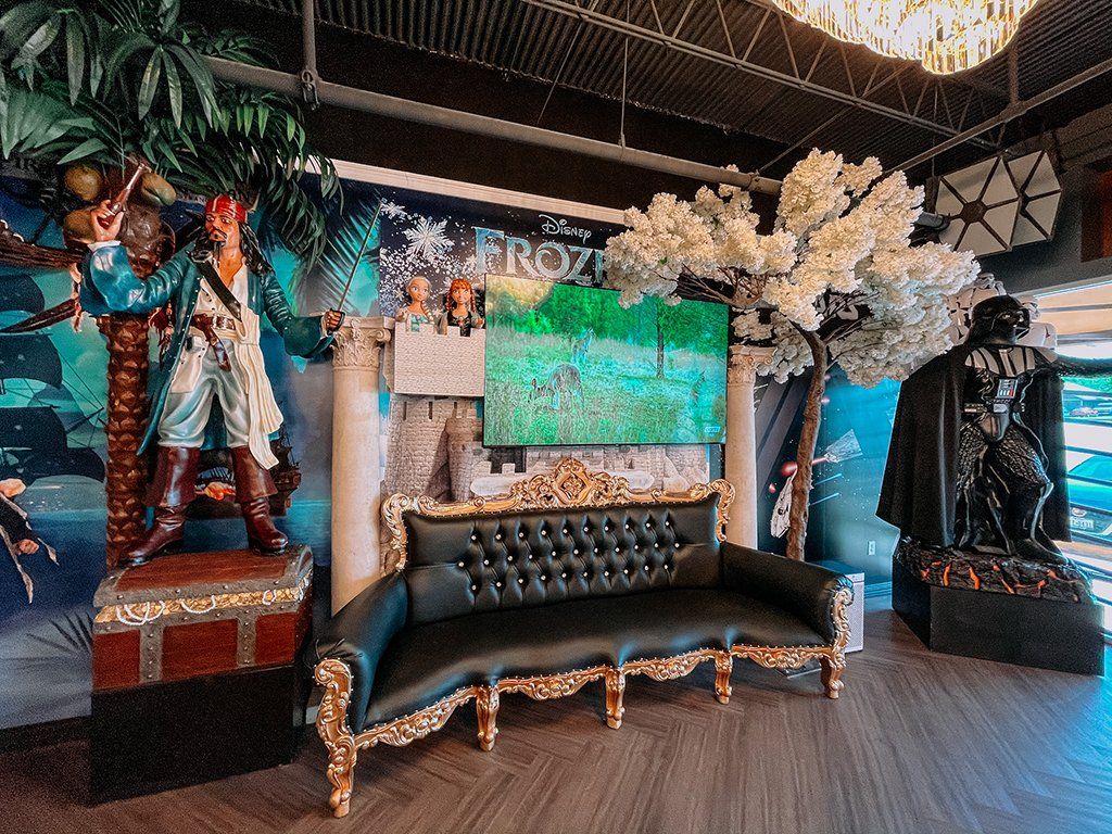Pirate and Darth Vader statues flank a tufted black couch in a themed interior.