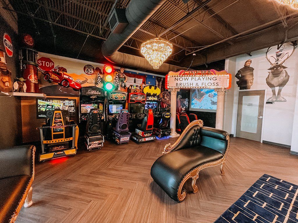A vintage arcade room with games, a chaise lounge, and decorative signs.