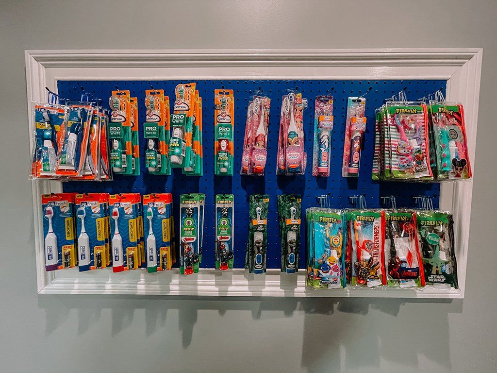 Toothbrushes on a blue pegboard display. Various colorful packages hang, organized inside a white frame.