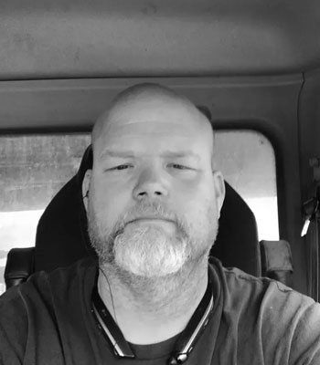 A man with a beard is sitting in the driver 's seat of a car.