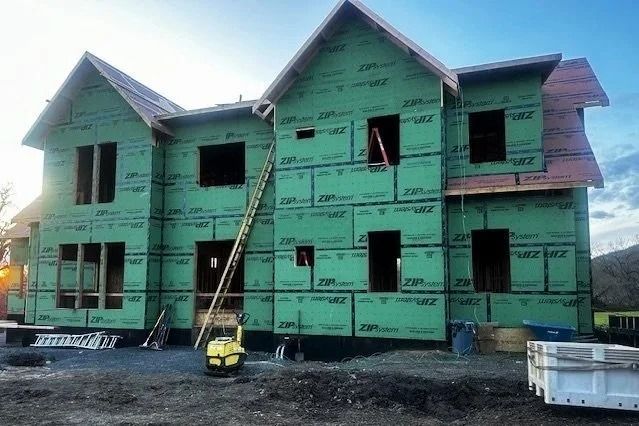 Partially built green house with scaffolding and ladder at a construction site