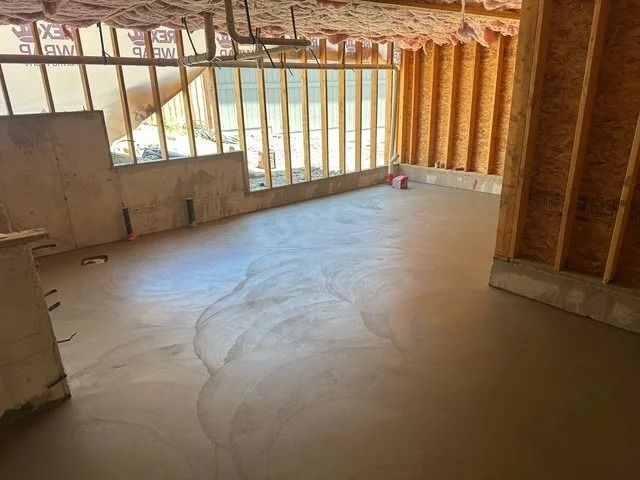 Unfinished room with exposed wooden framing, concrete floor, and large windows overlooking outside.