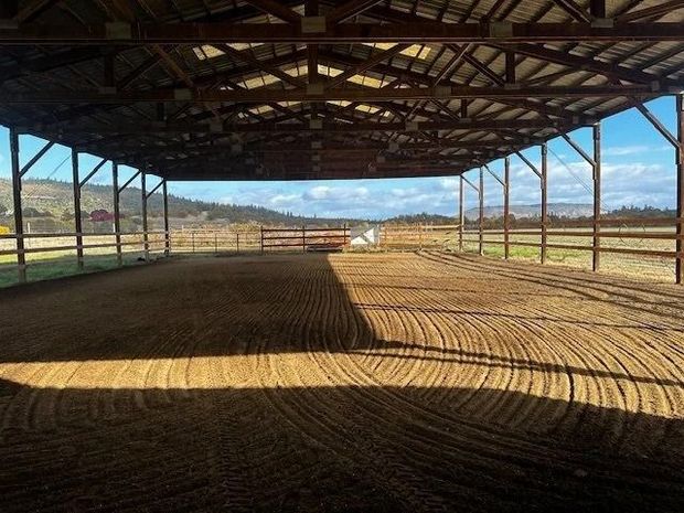 Open-sided barn with a dirt floor and sunlight casting long shadows inside