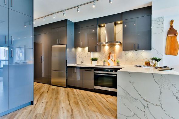 Modern kitchen with dark cabinets, marble island, stainless appliances, and wood flooring Modern kitchen with dark cabinets, marble island, stainless appliances, and wood flooring