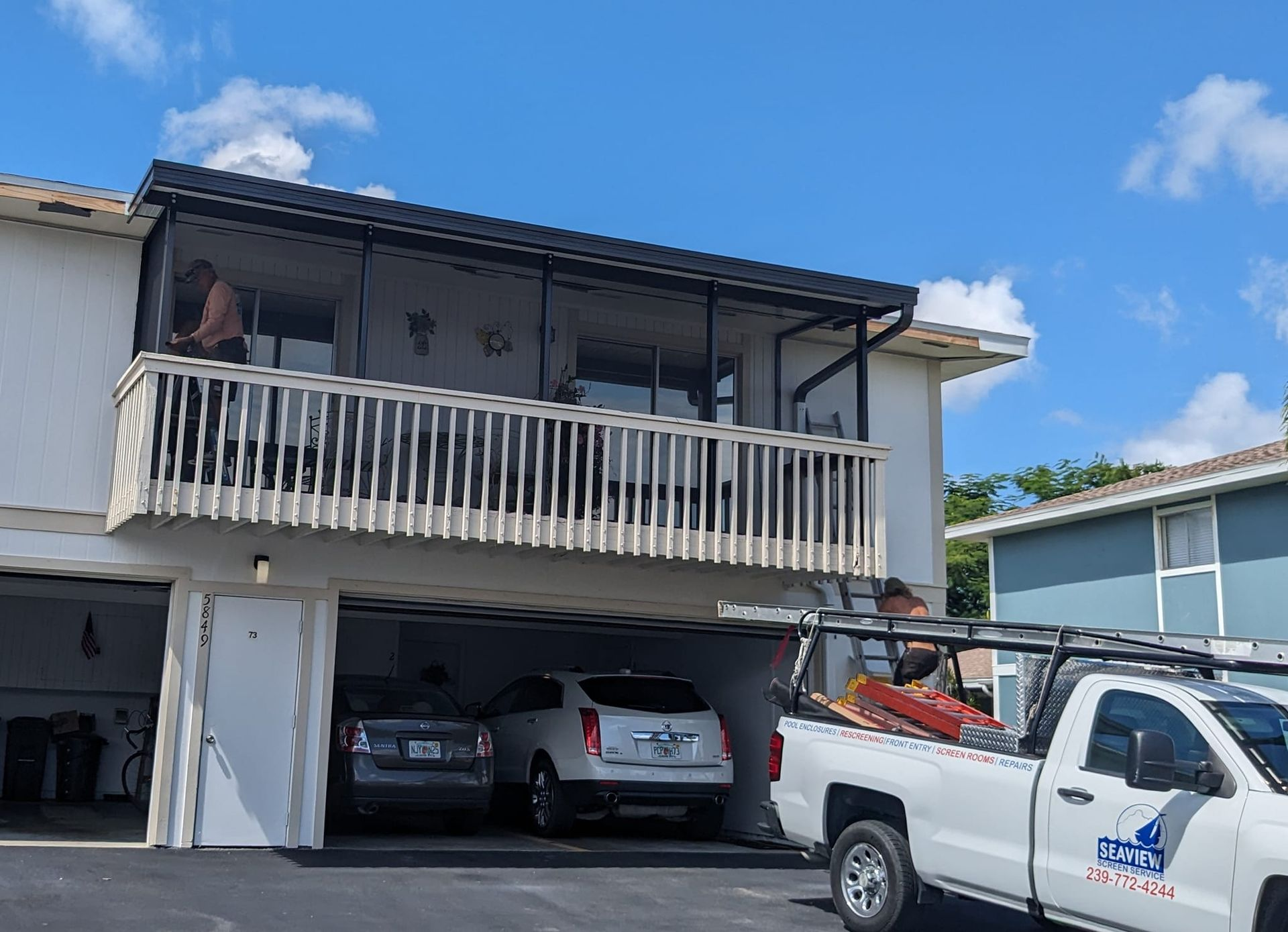 A white truck is parked in front of a house with a balcony.