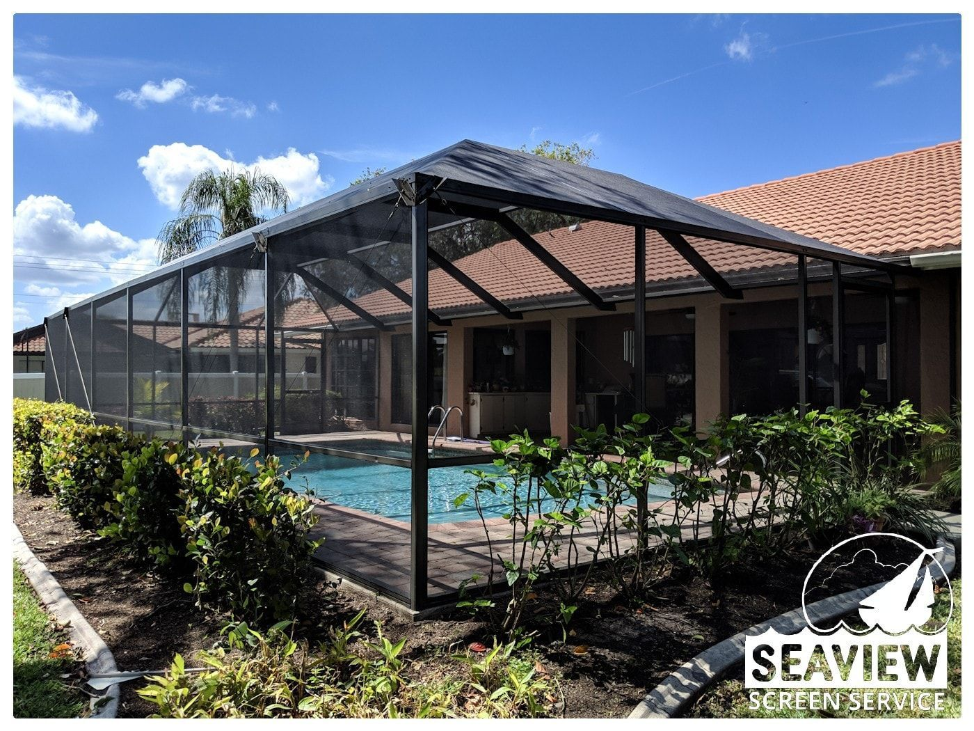 A screened in swimming pool in the backyard of a house.