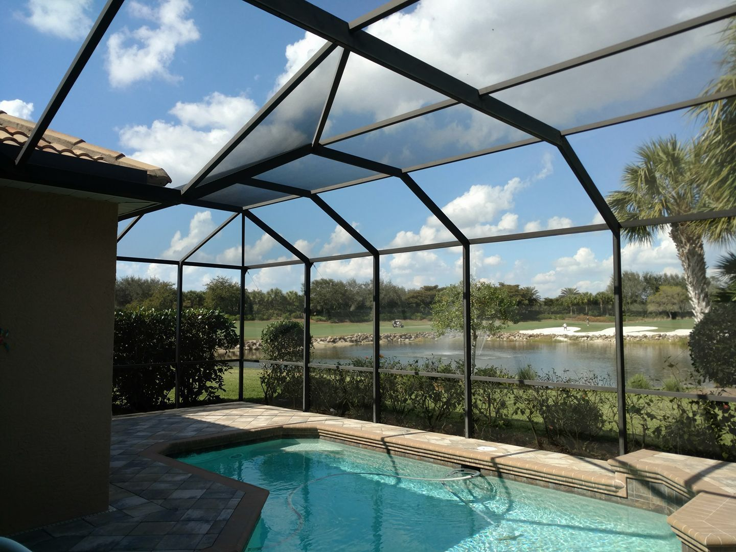 A screened in swimming pool with a view of a lake