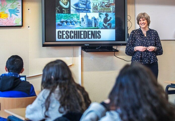 Janine Brandsen als docent voor de klas bij digibord met leerlingen van de achterkant gefotografeerd
