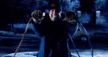 Man joyfully skiing in snowy neighborhood, holding poles, wearing hat and coat at night.