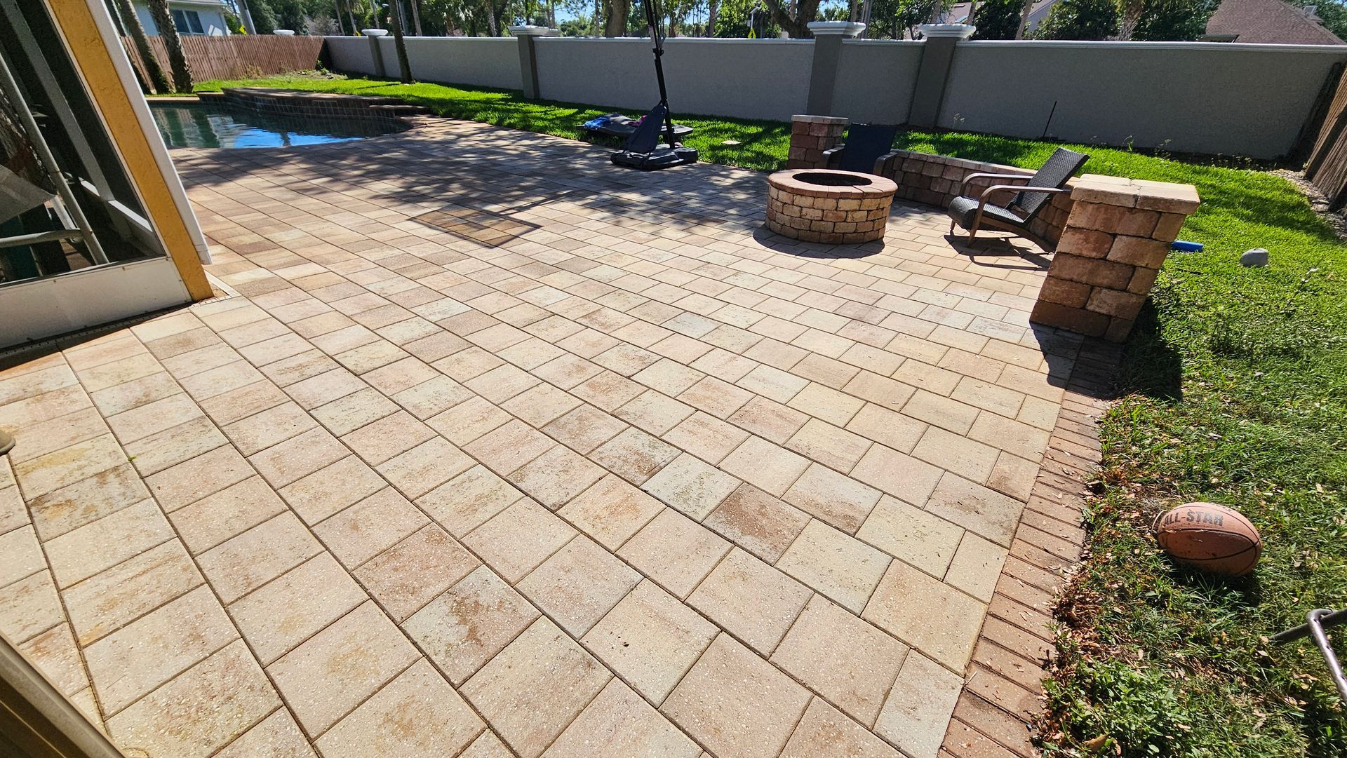 Brick patio with fire pit, chairs, and grass yard.