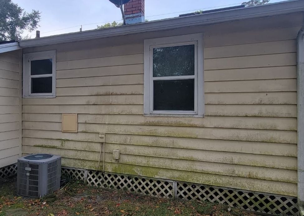 The side of a house with a dirty siding and a window.