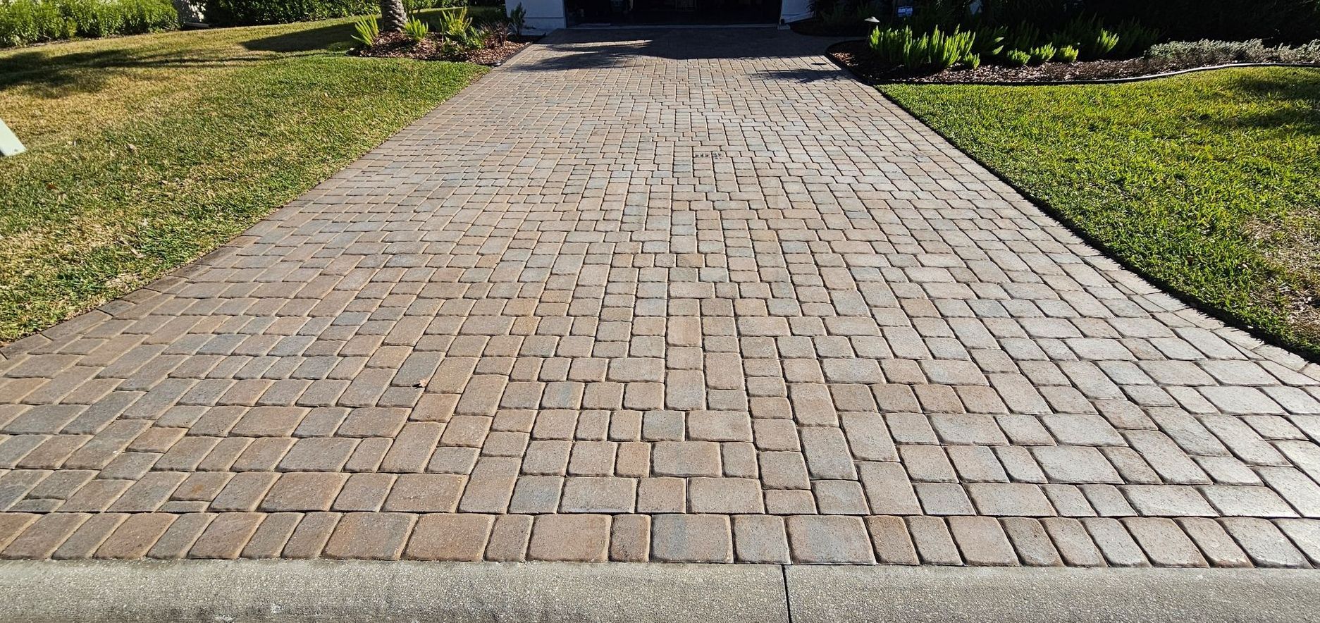 A driveway with bricks and a sidewalk in front of a house.