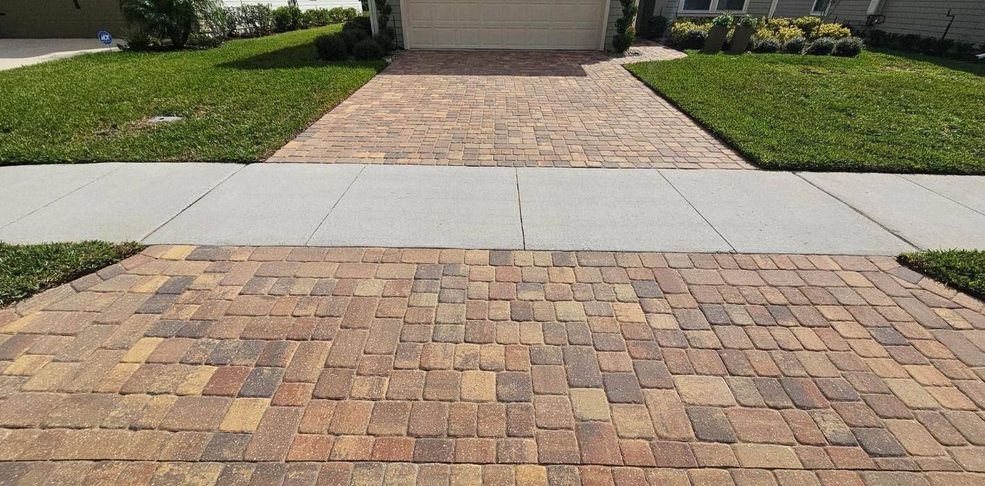 A driveway with bricks and a sidewalk in front of a house.