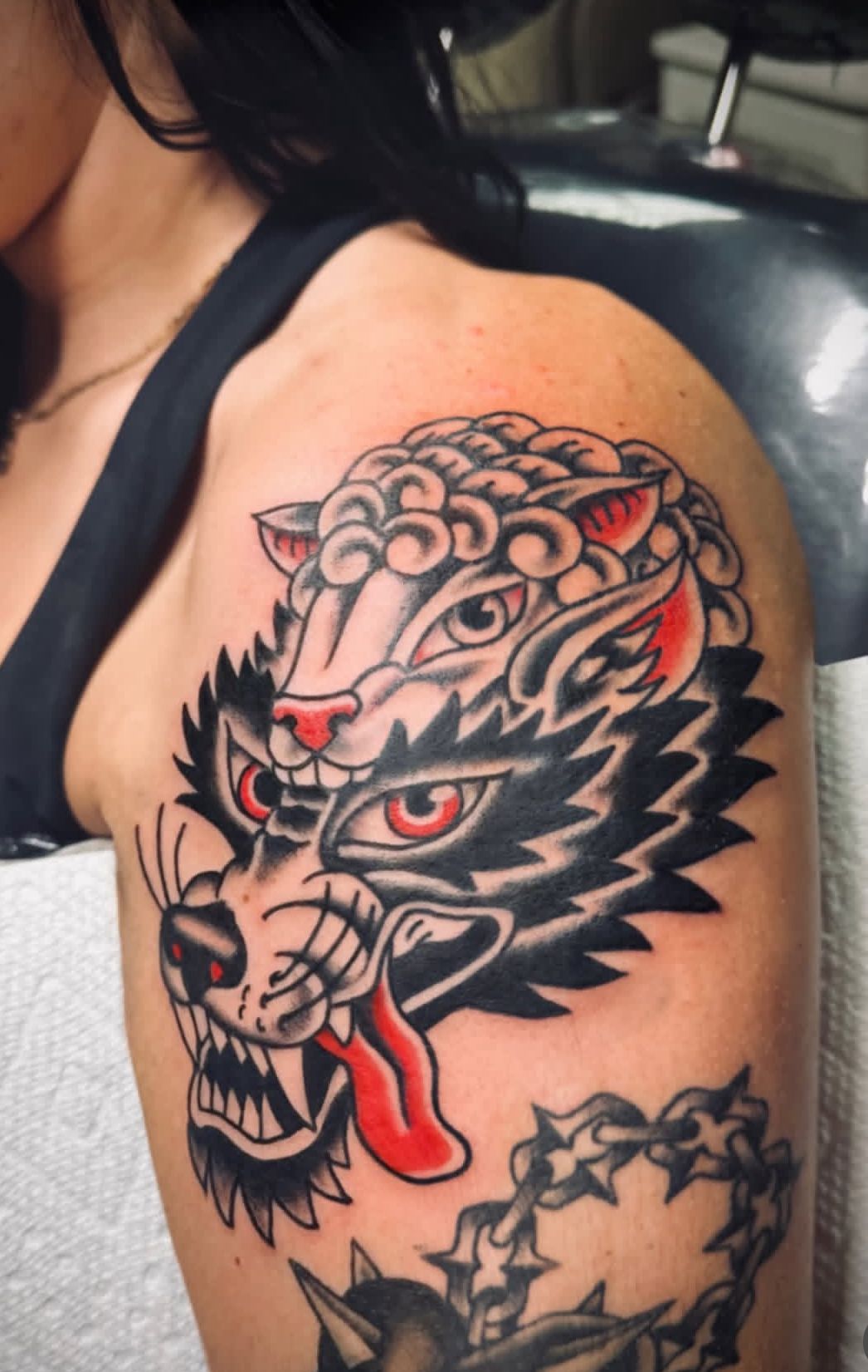 Dragon tattoo on upper arm and shoulder in black, red, and gray with a red tongue and swirling details