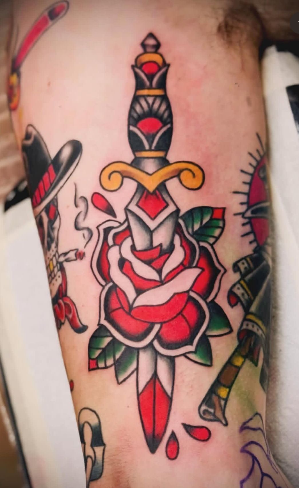 Colorful traditional dagger tattoo with red rose and heart on skin
