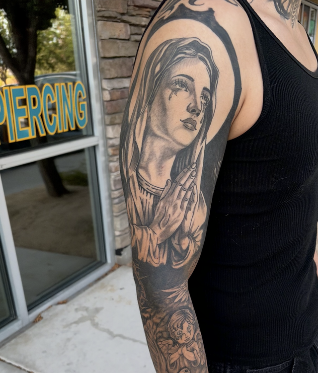 Arm tattoo of a woman’s portrait on a person standing outside a piercing shop