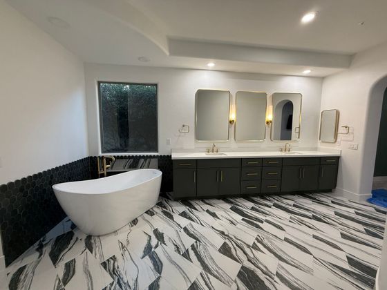 Modern bathroom with black vanity, round tub, mirrors, and black-and-white patterned floor tiles