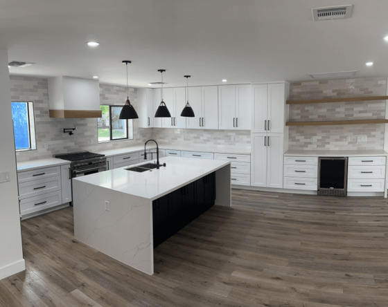 Bright modern kitchen with white cabinets, black pendant lights, and a large island with sink