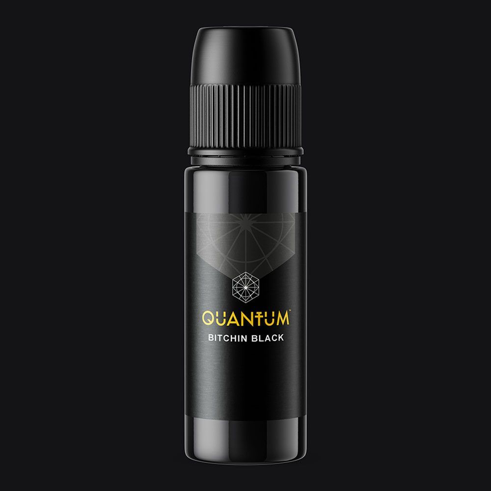A black bottle of Quantum tattoo ink with a geometric logo and gold text on a dark background.
