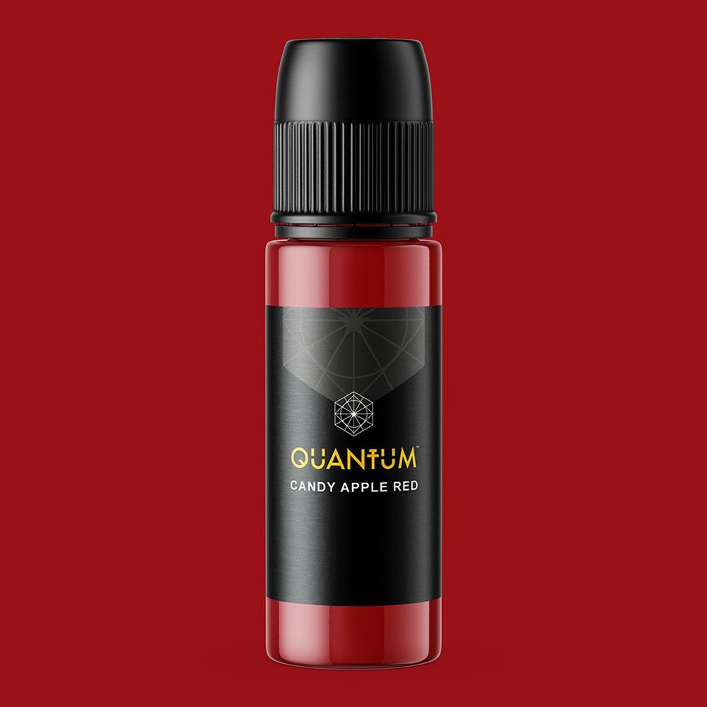 A bottle of Quantum brand tattoo ink in the color Candy Apple Red, featuring a black label with gold lettering.