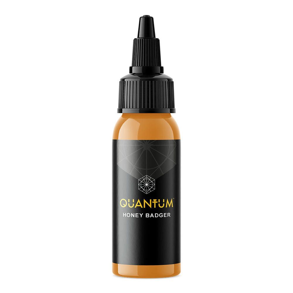 A bottle of Quantum brand tattoo ink in the color Honey Badger, featuring a black label with gold text on a white background.