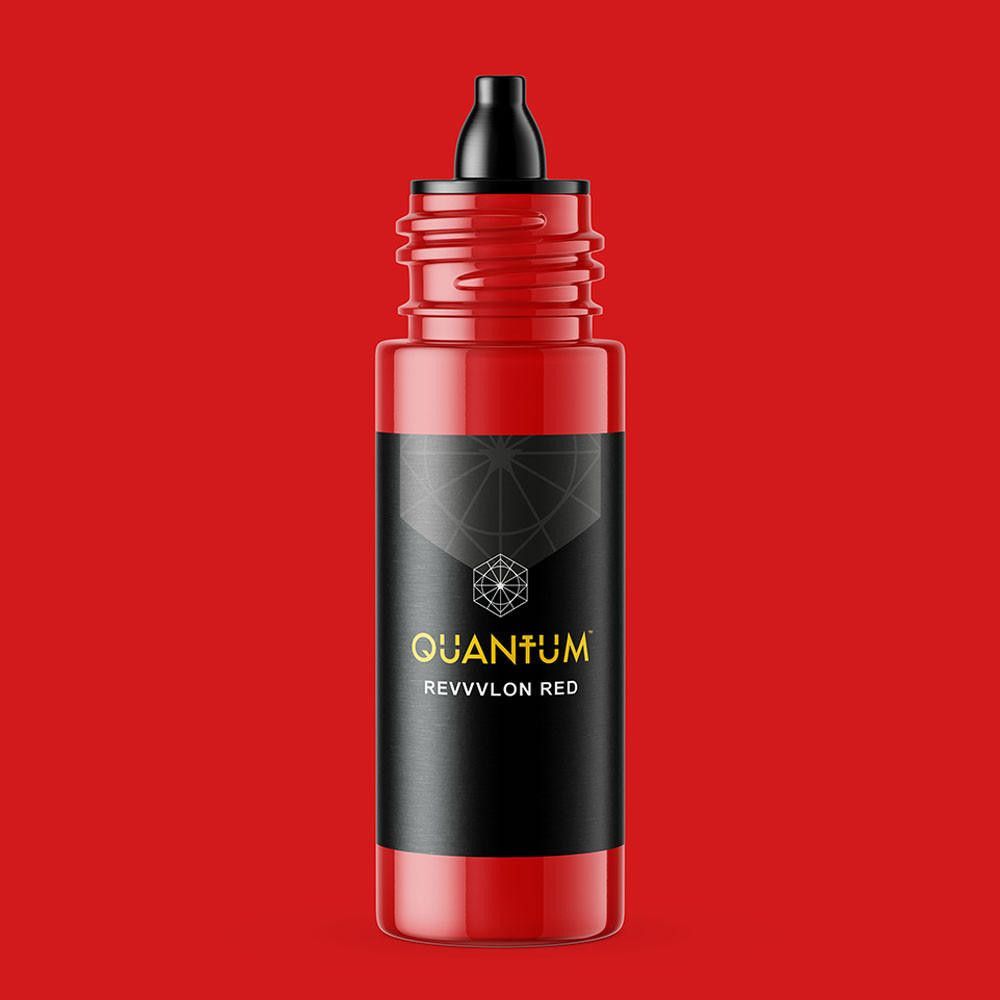 A bottle of Quantum Revlon Red tattoo ink with a black label, set against a matching vibrant red background.