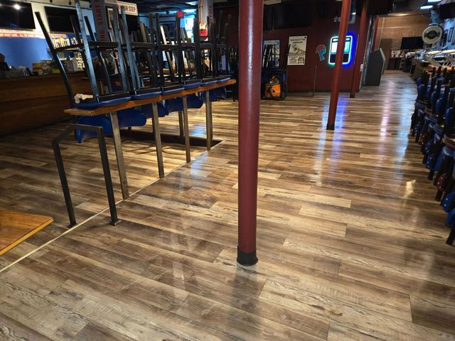 A restaurant with wooden floors and tables and chairs stacked on top of each other.