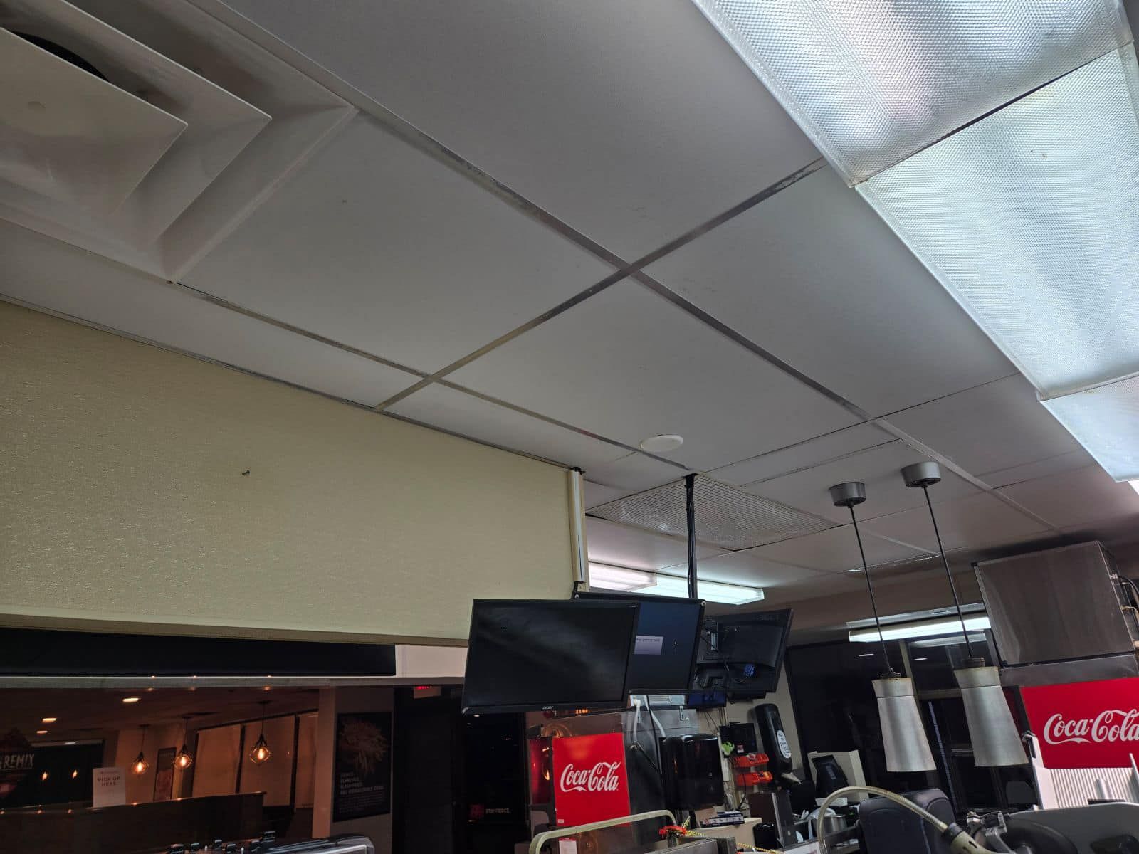 A coca cola sign hangs from the ceiling of a restaurant