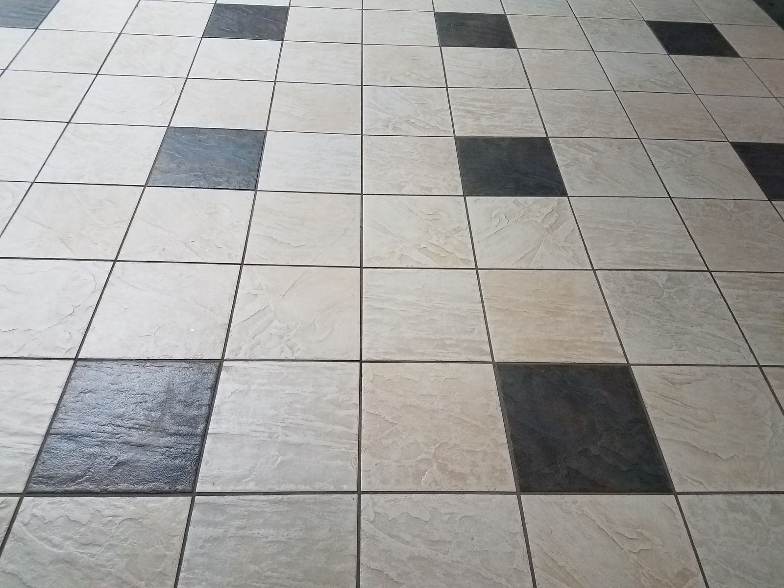 Checkerboard-patterned tiled floor with scattered dark gray and black squares.