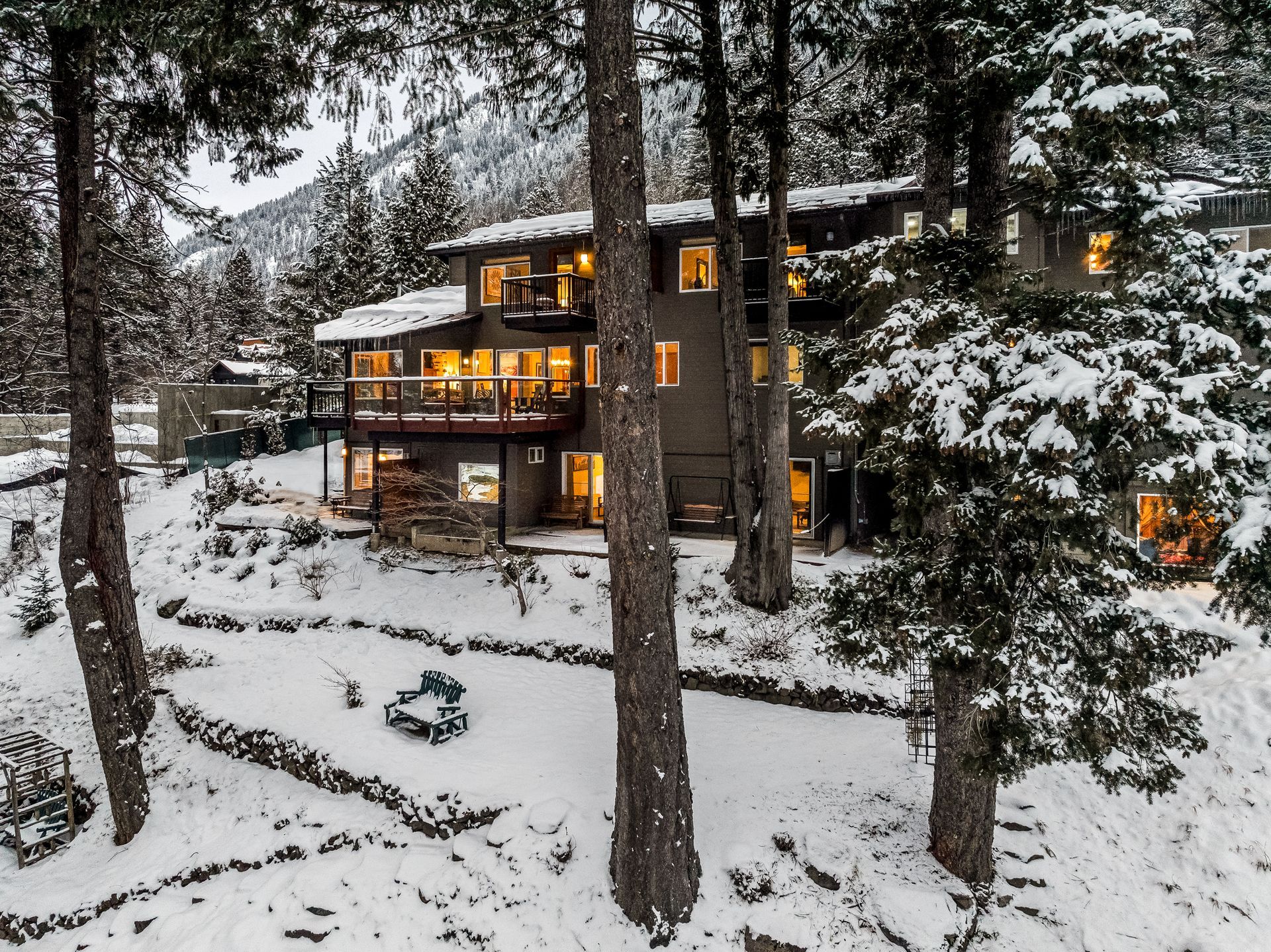 Snow-covered hotel nestled among trees, windows lit
