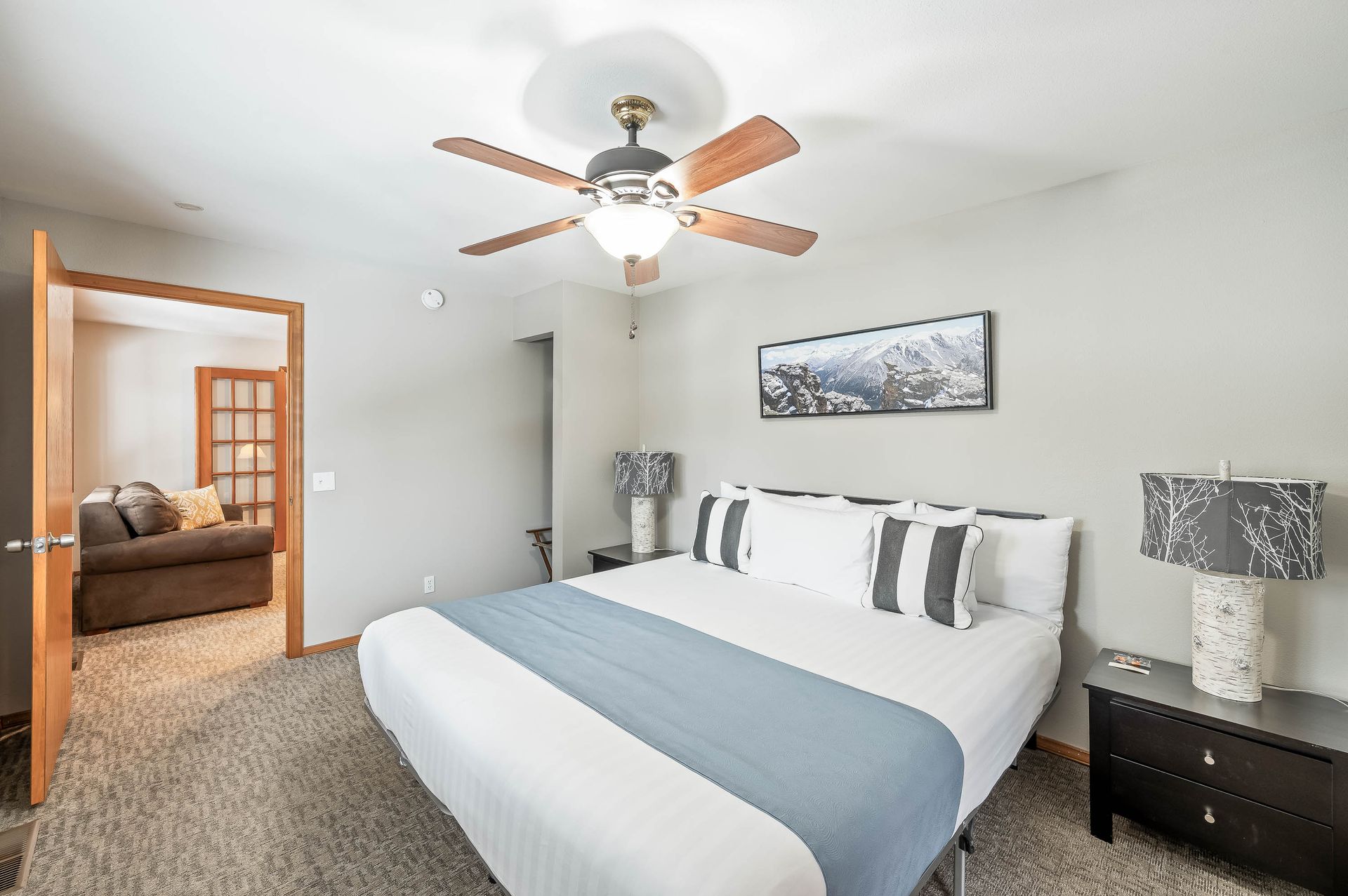 Bedroom with a large bed, gray walls, and a door leading to a sitting area.