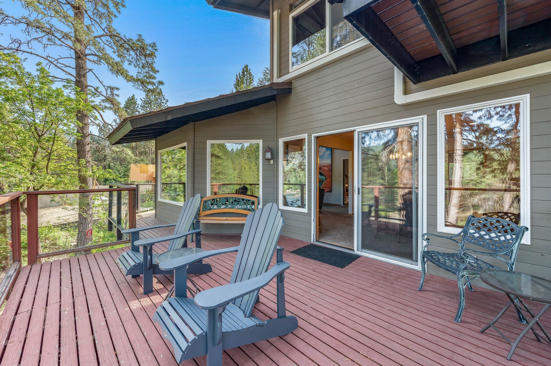 Deck with Adirondack chairs in front of a hotel in Leavenworth with sliding glass doors and a forest backdrop.