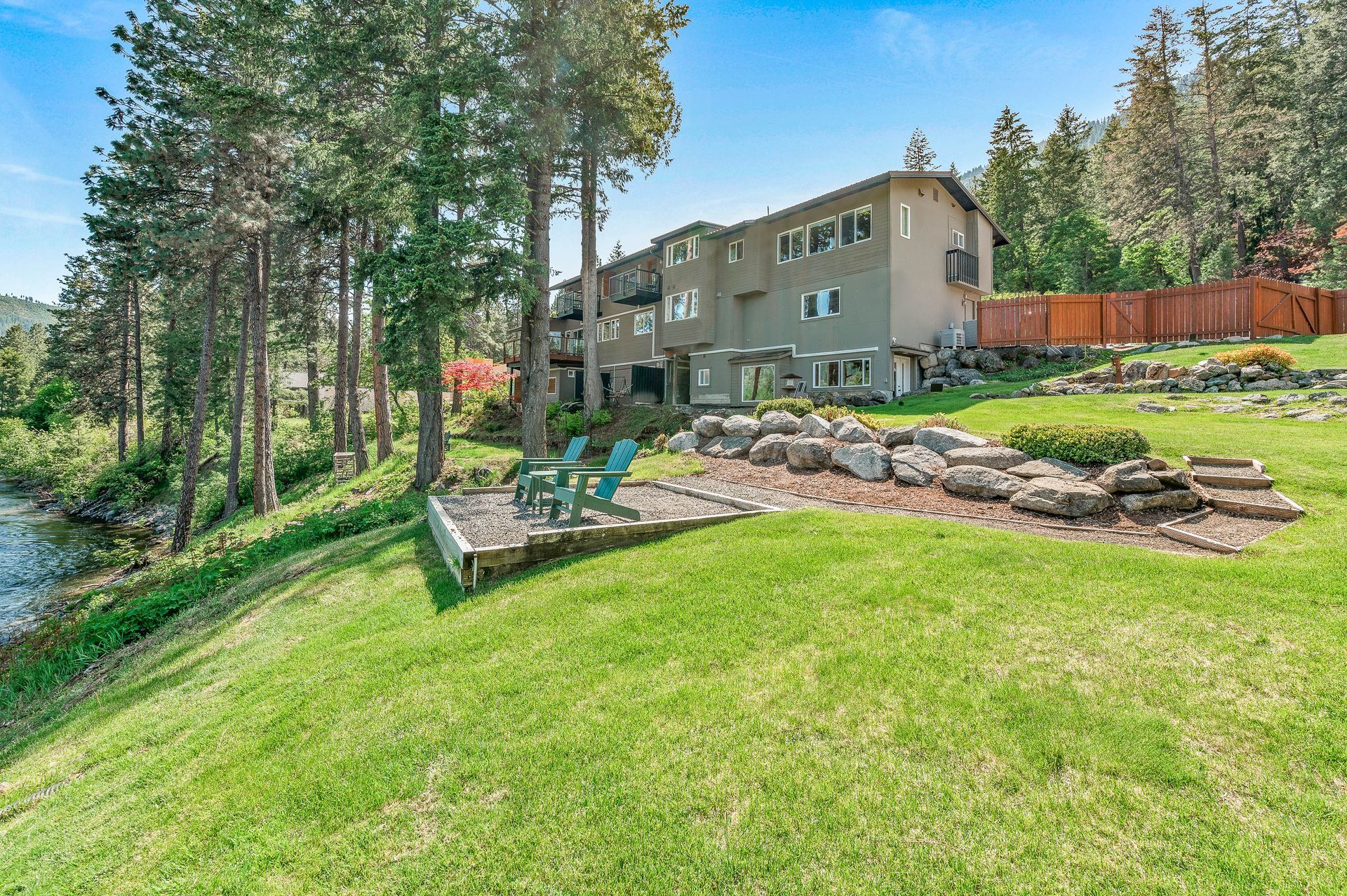 Hotel on a grassy hill overlooking a body of water.  Two blue chairs sit on a patio area.