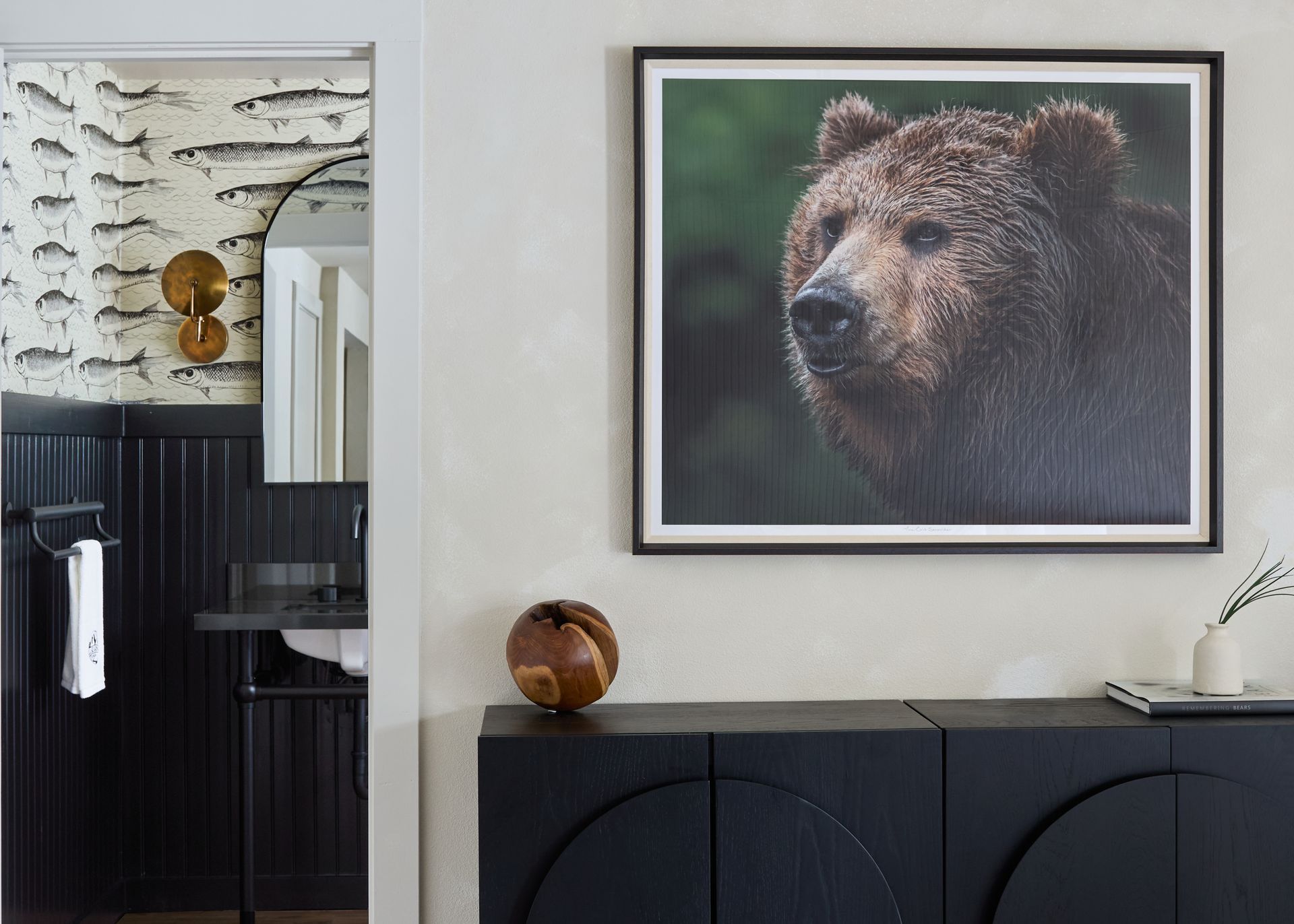 Modern room with bear portrait above a dark cabinet and a glimpse of a patterned bathroom mirror area