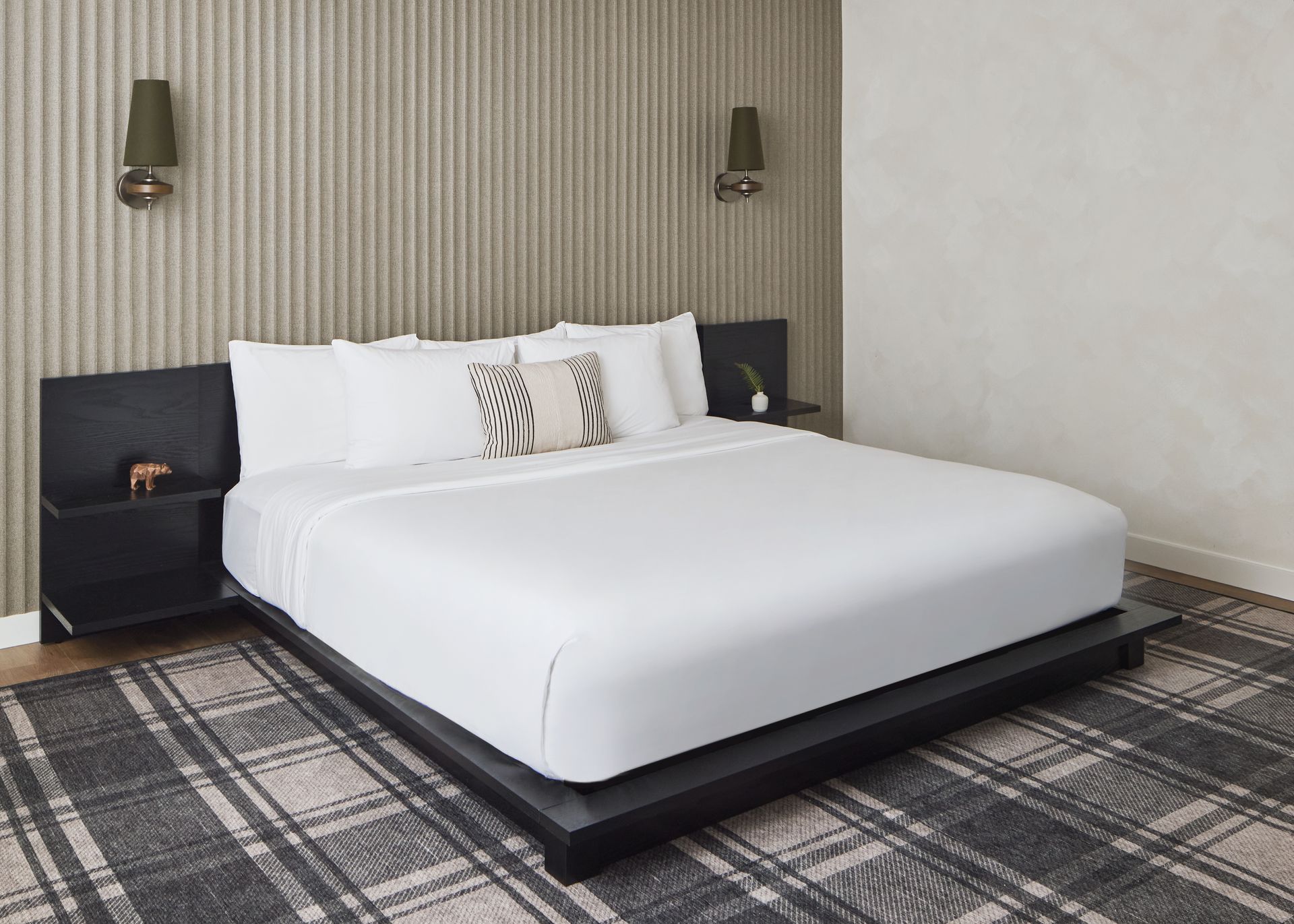 Modern bedroom with white bed, dark headboard, bedside lamps, and patterned rug