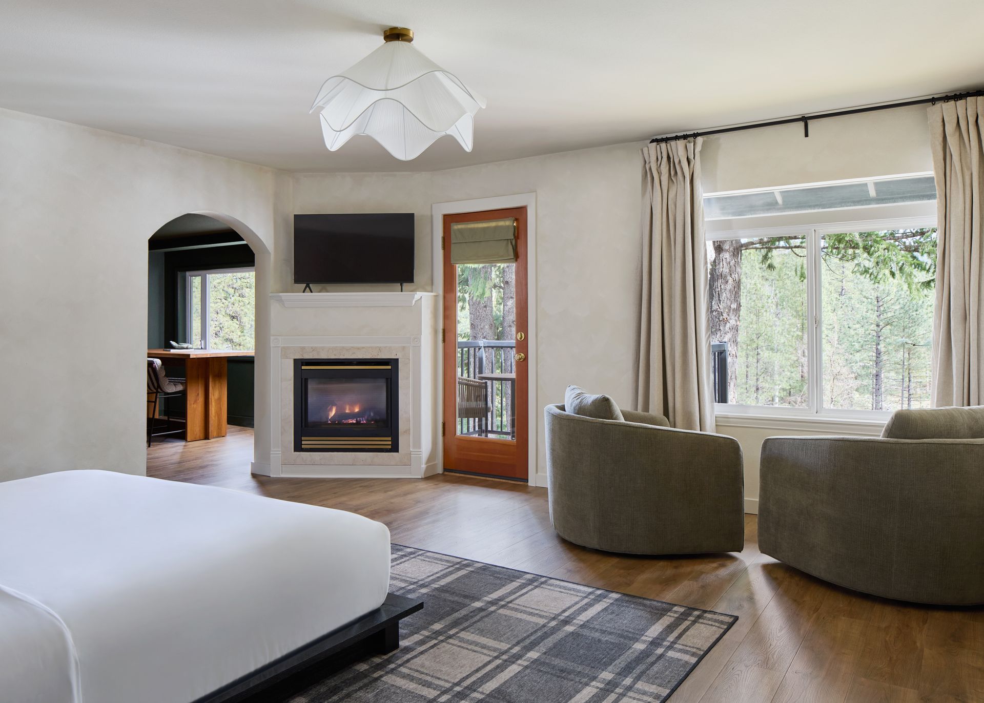 Modern living room with fireplace, TV, large windows, and two green chairs