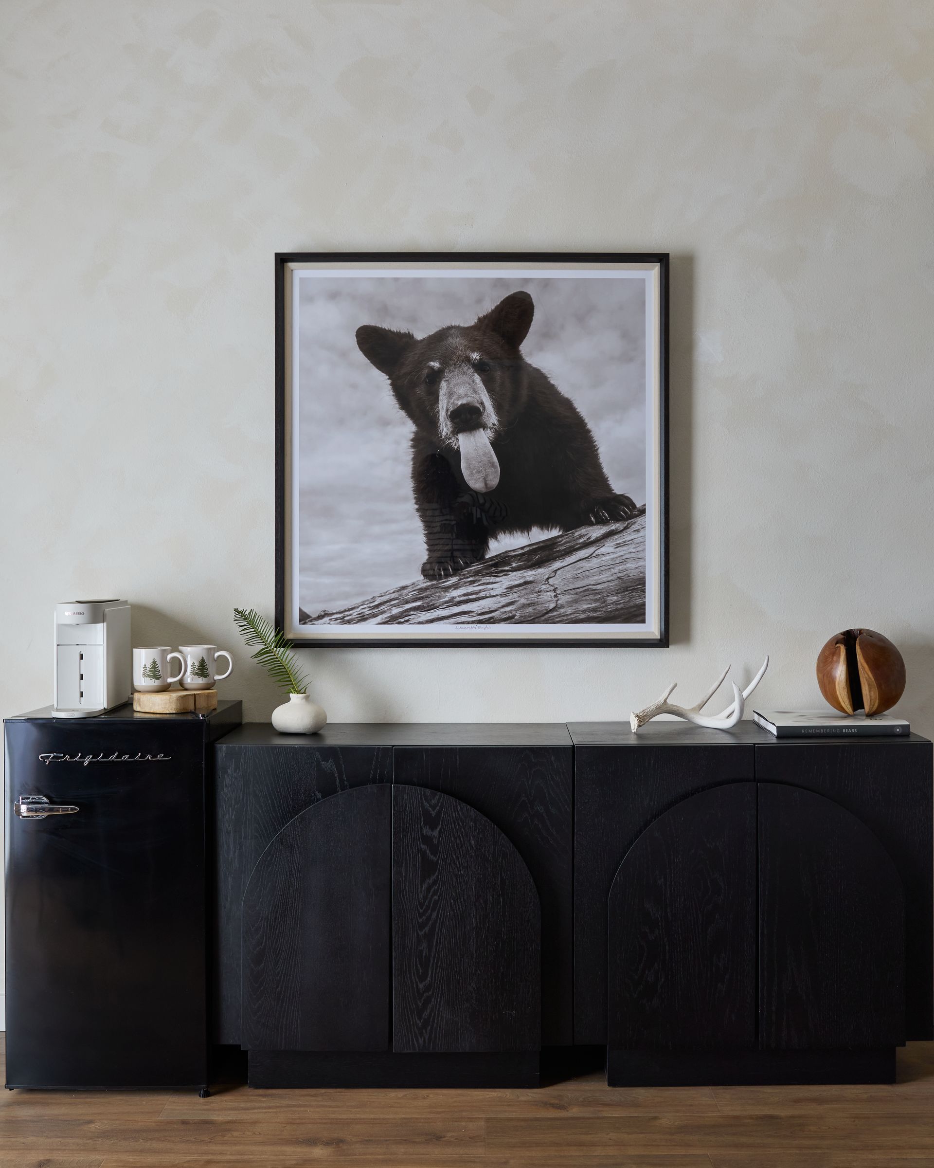 Black bear artwork above a black sideboard with decor in a minimalist room