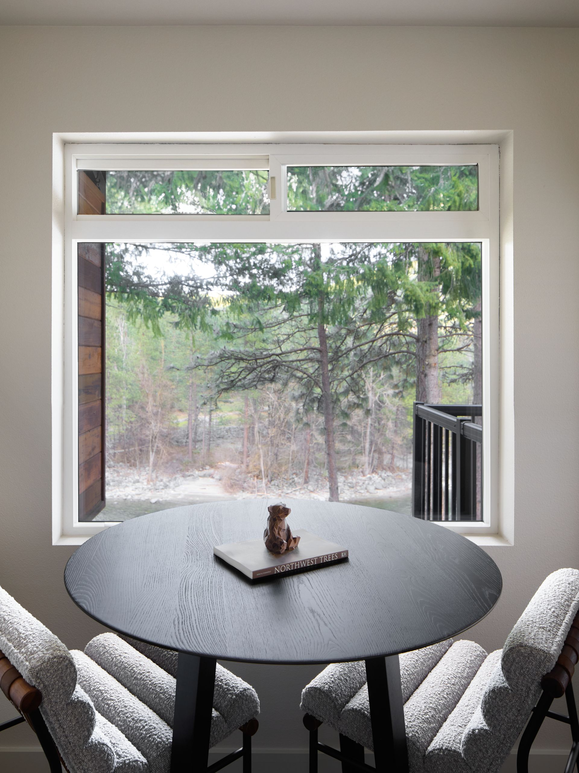 Modern room with round table and chairs by a large window overlooking trees