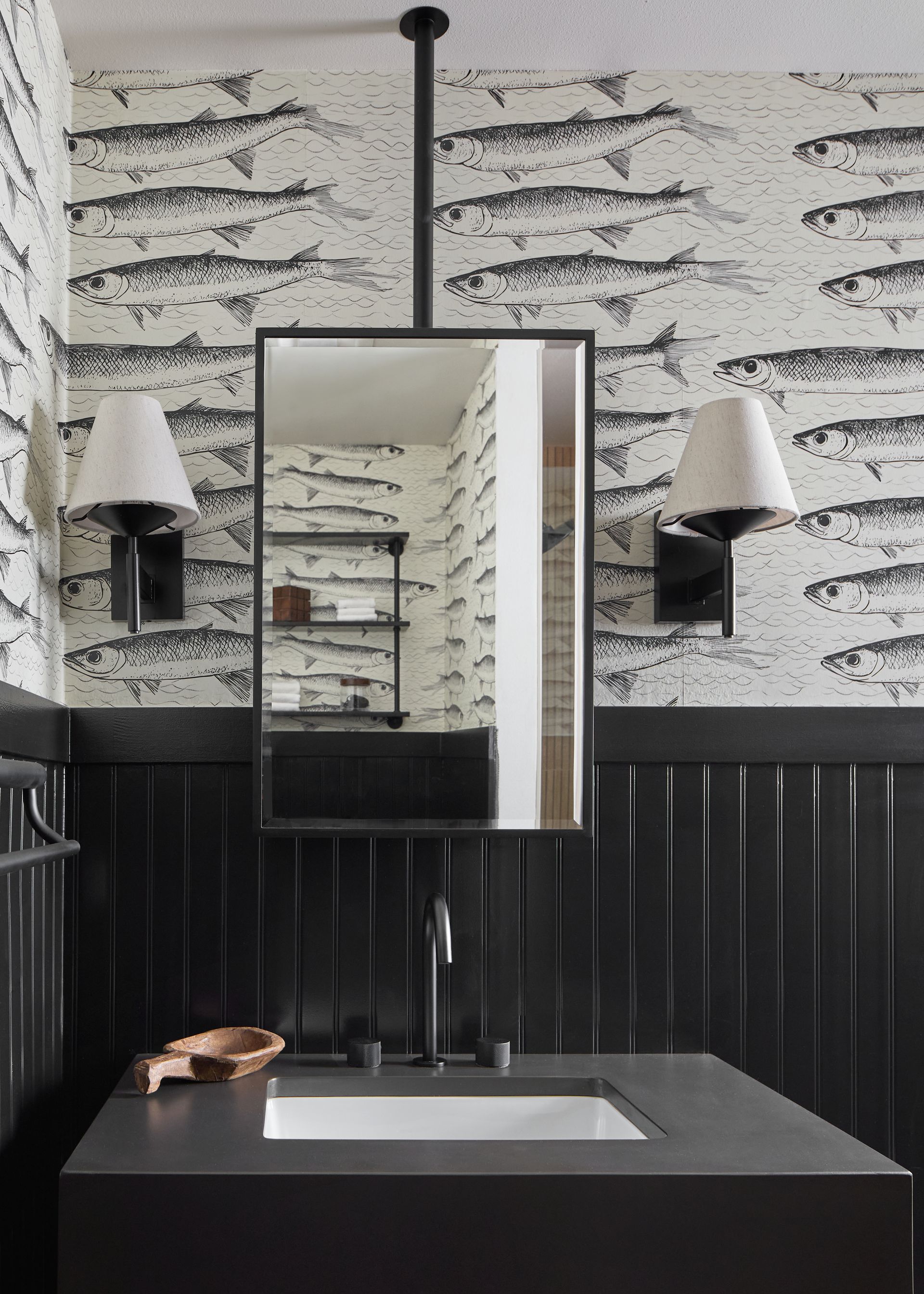 Modern black-and-white bathroom vanity with mirror, sink, wall sconces, and patterned wallpaper