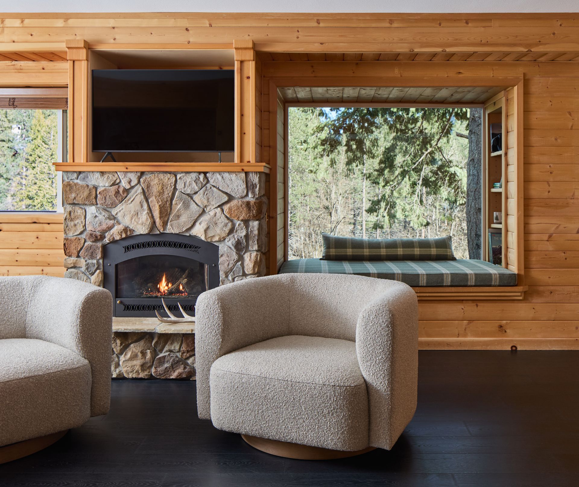 Cozy hotel room with stone fireplace, large window, and two curved beige chairs