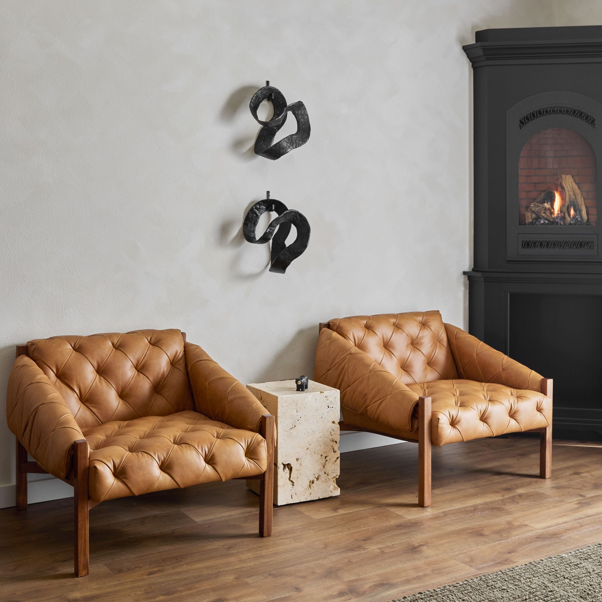 Two tan leather armchairs beside a black fireplace in a modern living room