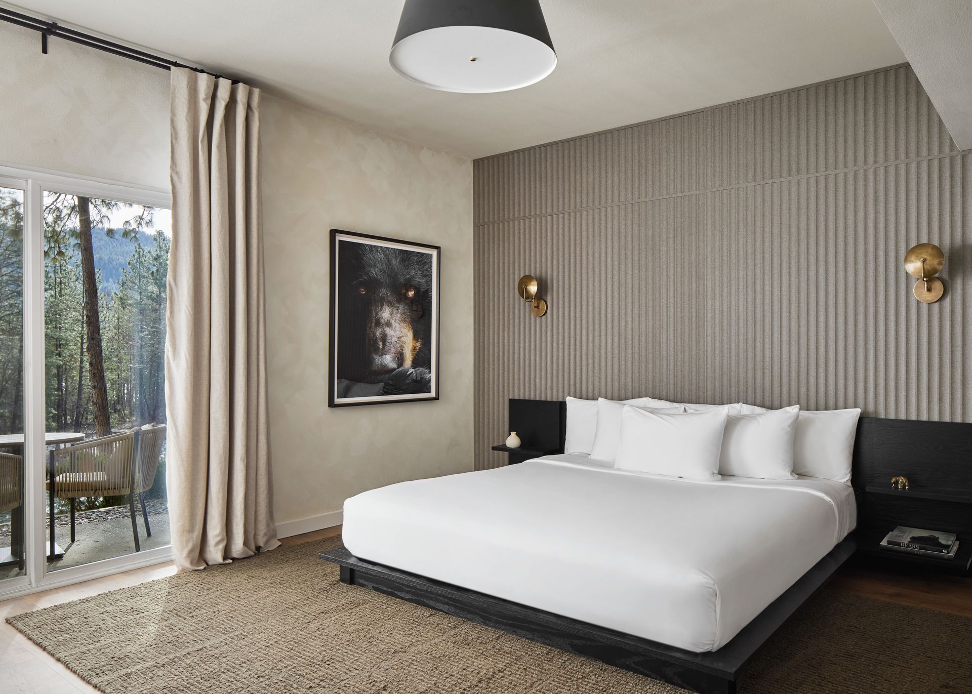 Modern bedroom with a low bed, striped accent wall, balcony doors, and neutral decor