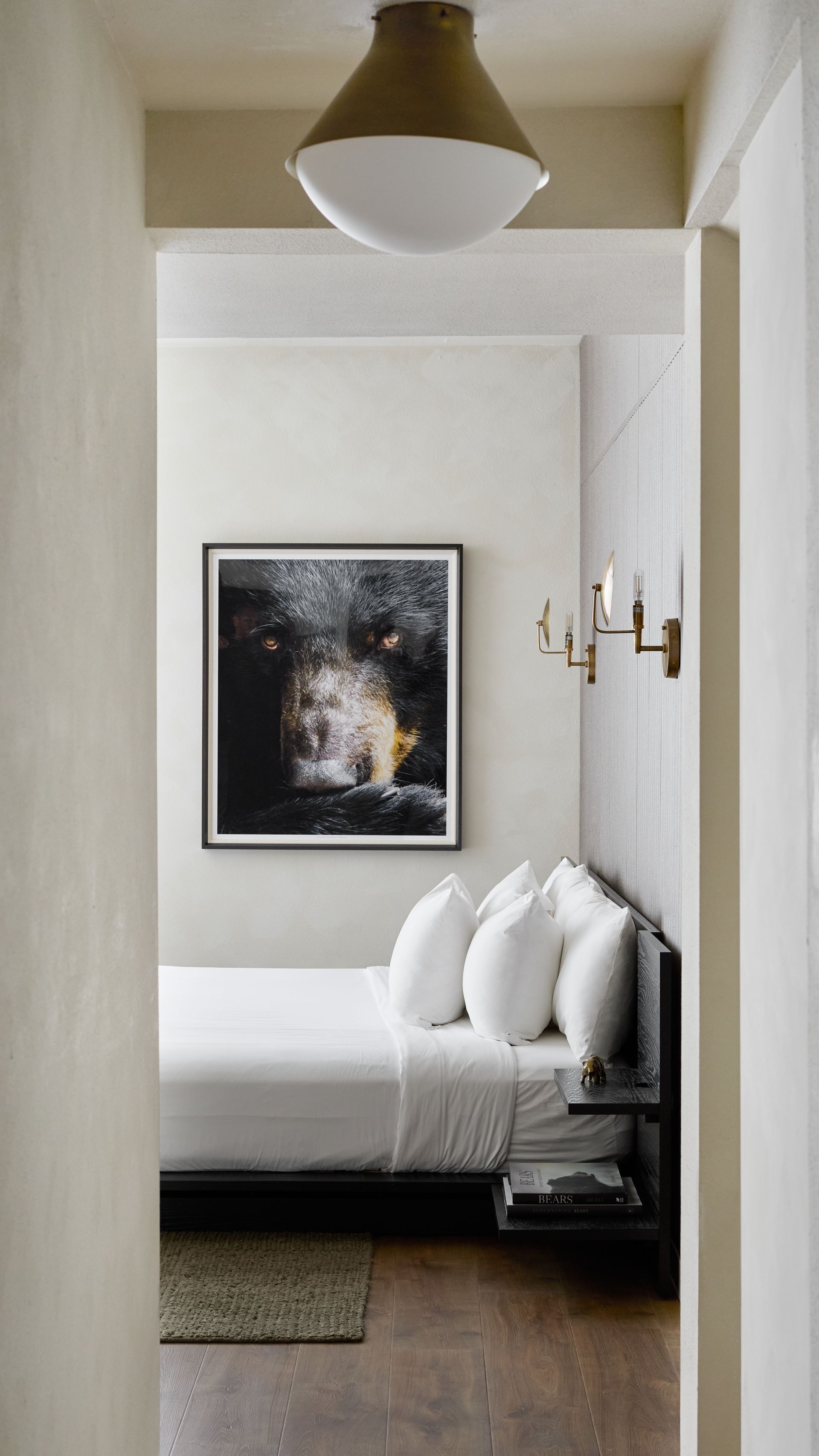 Minimalist bedroom nook with white walls, black-framed art, and a white daybed with pillows.