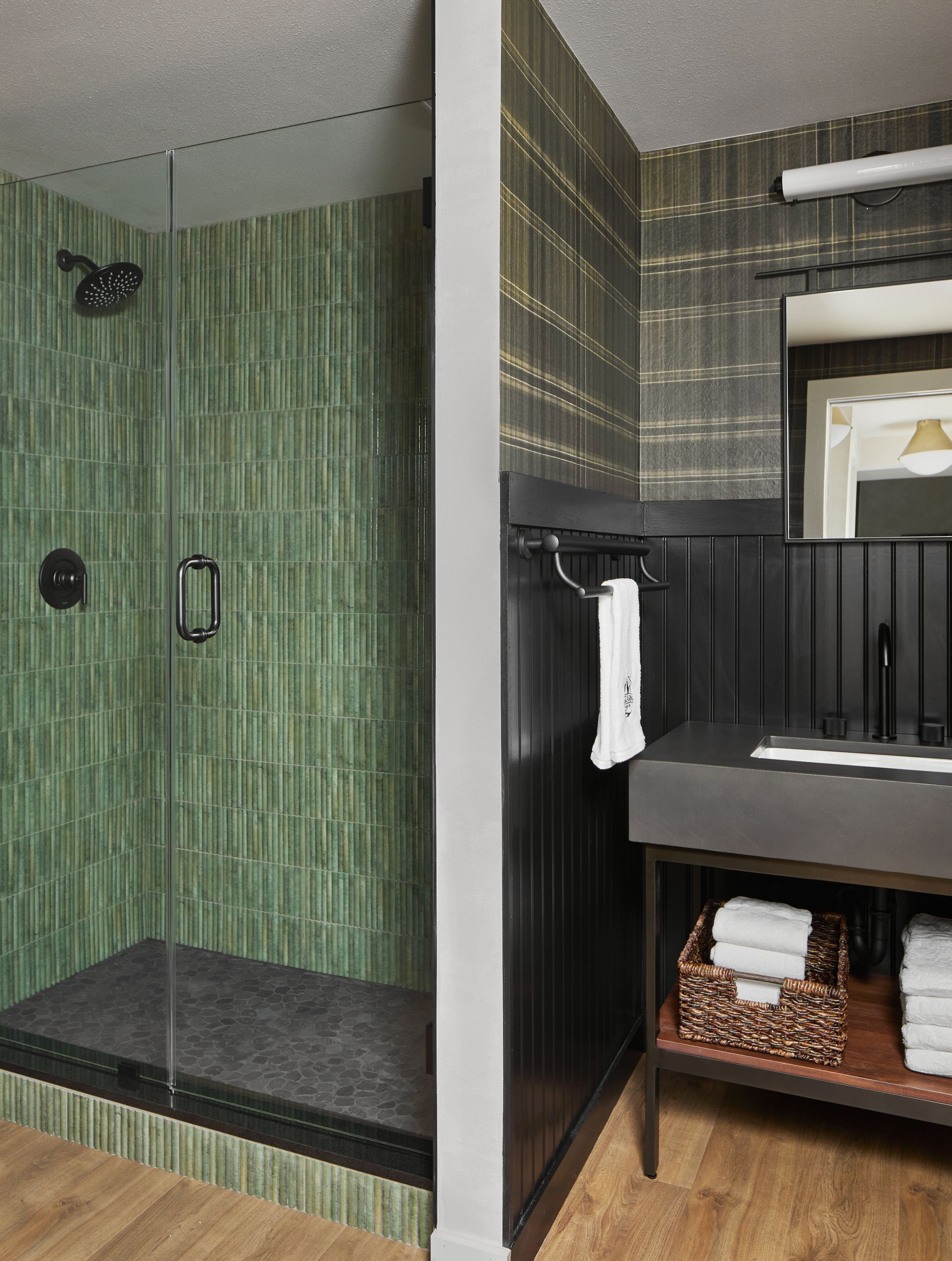 Modern bathroom with glass shower, black bench, and vanity with sink and towels