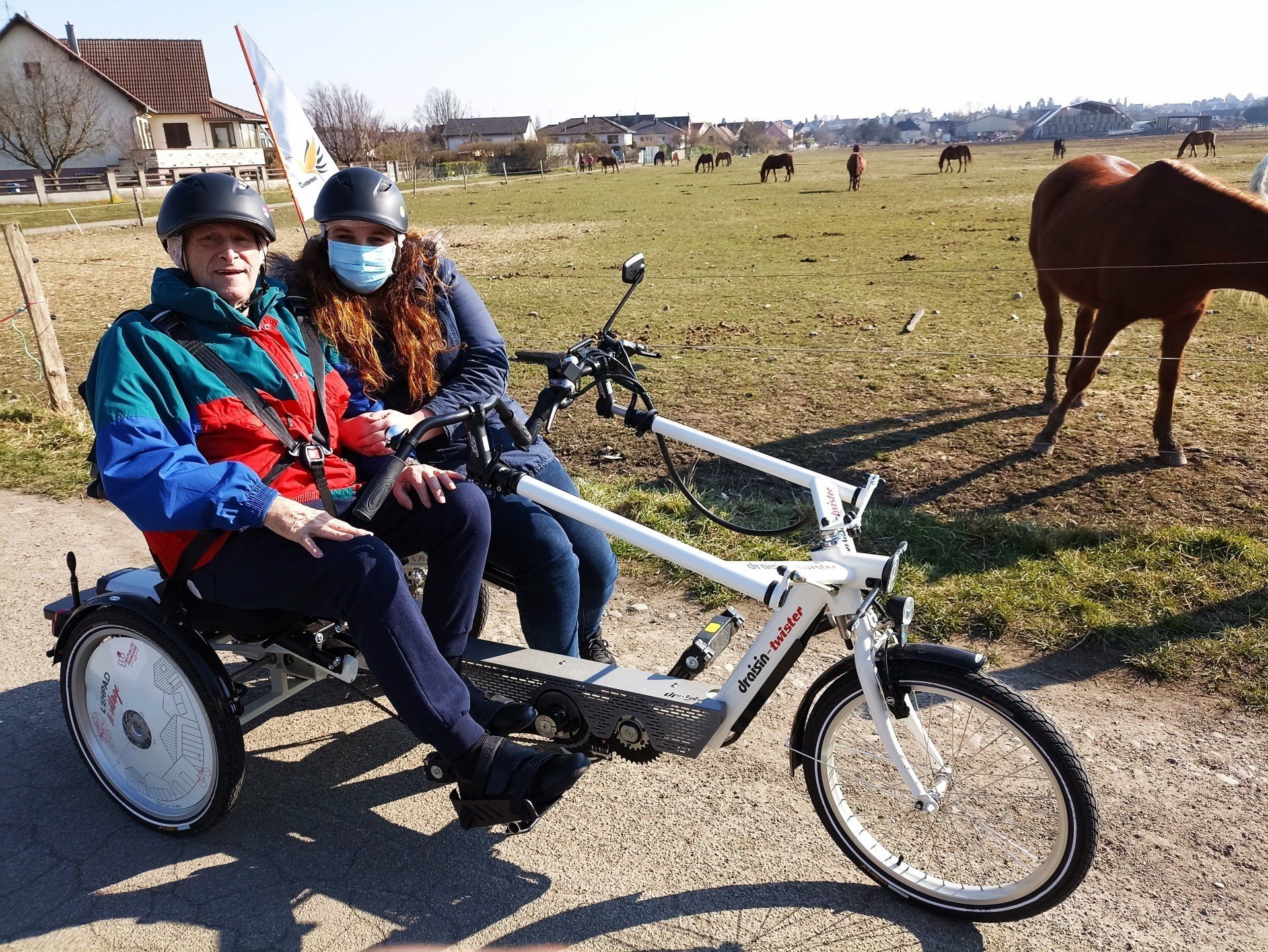 Un homme et une femme sont assis sur un vélo avec un cheval en arrière-plan.