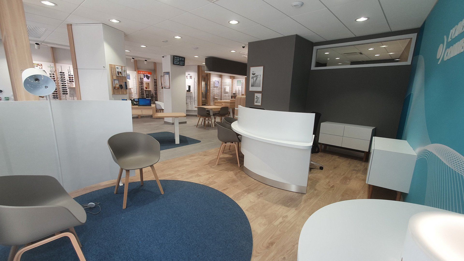Une pièce avec un tapis bleu, des chaises, des tables et un comptoir.