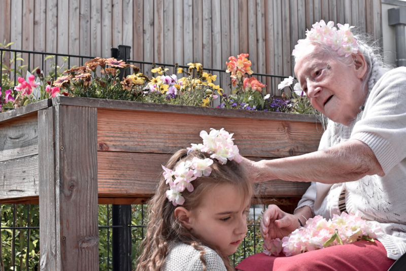 Une femme âgée met une couronne de fleurs sur la tête d'une petite fille.