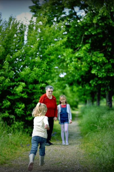 Une femme et deux enfants marchent sur un chemin dans les bois.