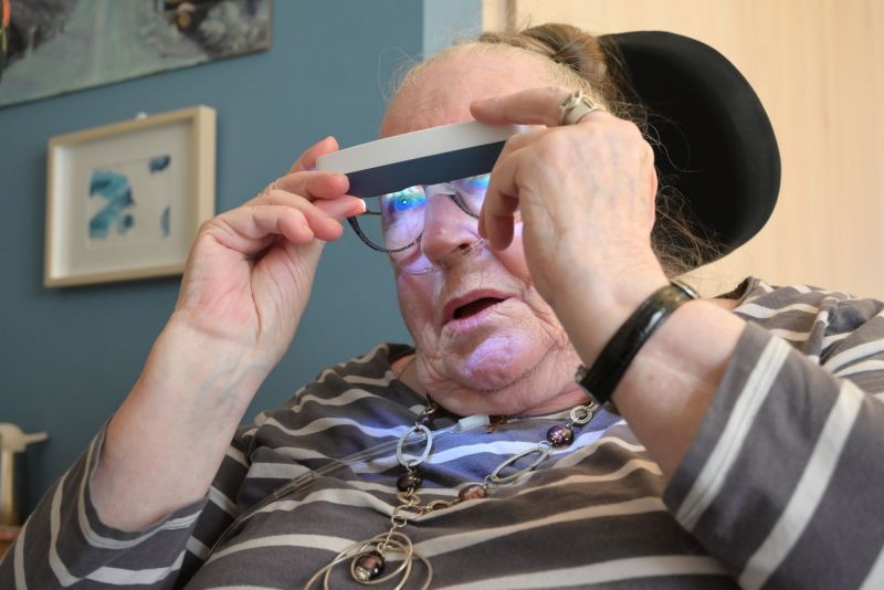 Une femme âgée porte une paire de lunettes avec une lumière dessus.